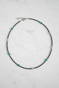 Black beaded necklace on a white fabric background