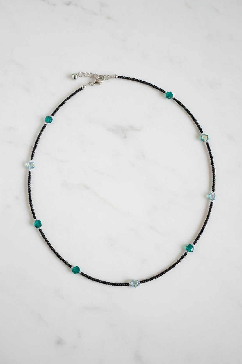 Black beaded necklace on a white fabric background