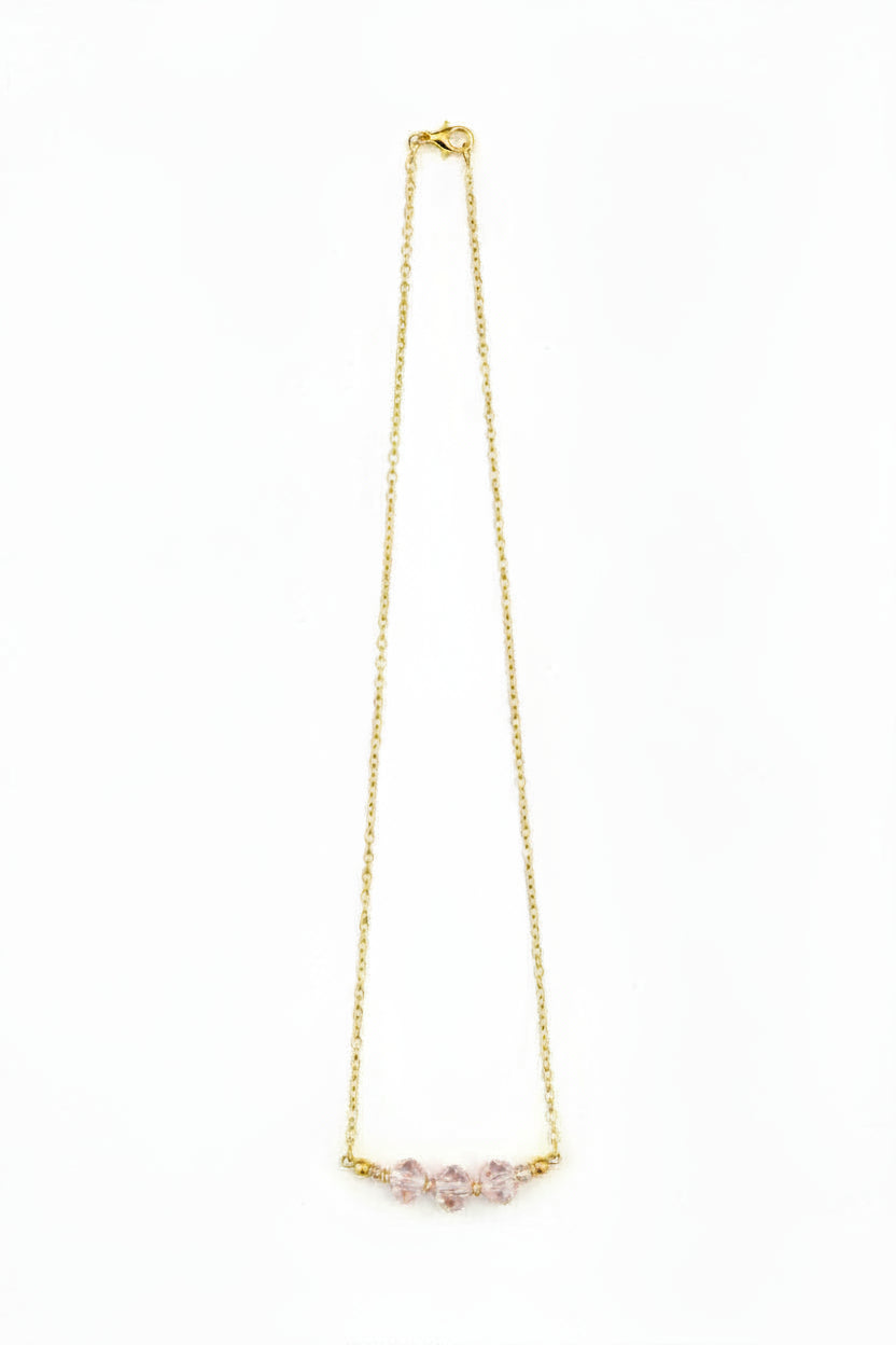 Gold necklace with pink gemstones on a white background