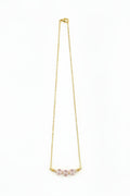Gold necklace with pink gemstones on a white background