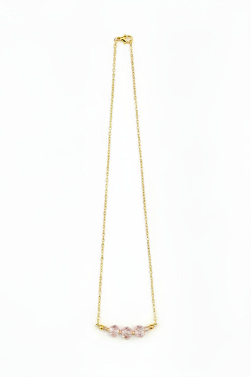 Gold necklace with pink gemstones on a white background