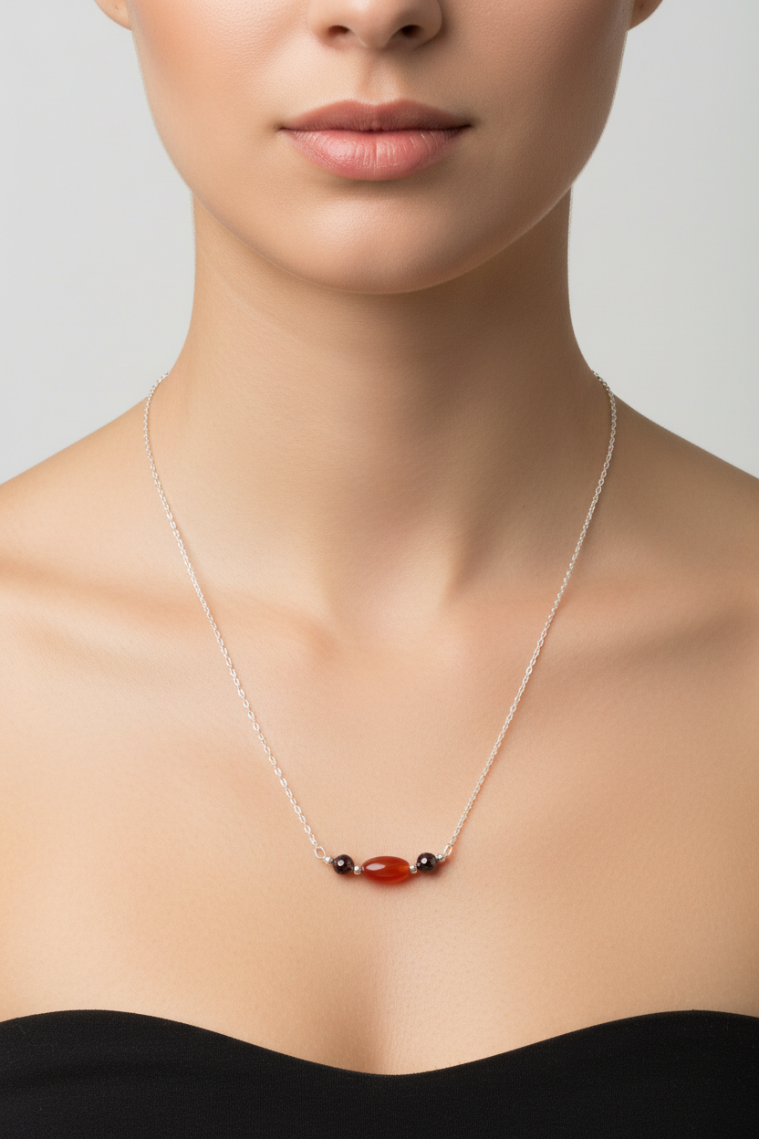 Necklace with red and black beads worn by a person on a neutral background