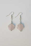 A pair of dangle earrings featuring light pink rose quartz flower-shaped beads suspended from silver fishhook wires, shown on a plain light gray background.