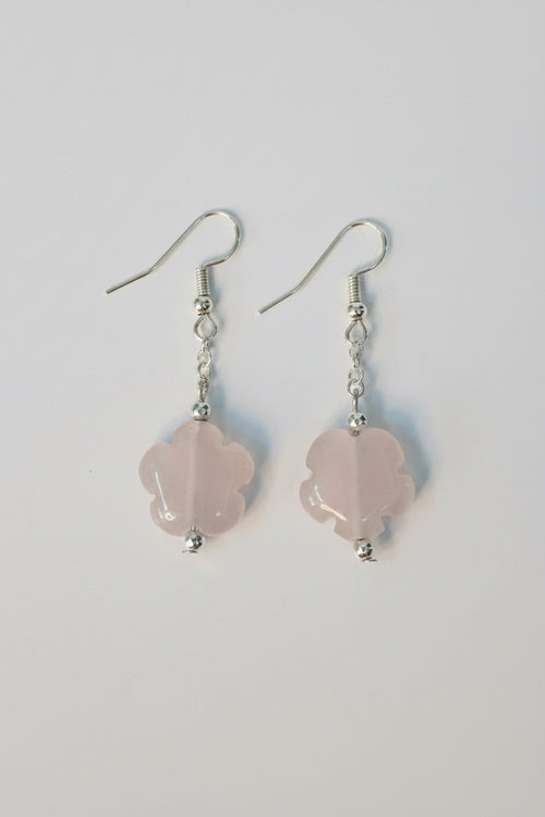 A pair of dangle earrings featuring light pink rose quartz flower-shaped beads suspended from silver fishhook wires, shown on a plain light gray background.