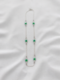 Necklace with green beads on a white fabric background