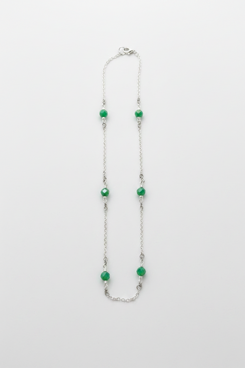 Necklace with green beads on a white fabric background
