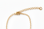 A close-up of a gold chain necklace showing the lobster clasp, extender chain, and ring closure on a plain white background.