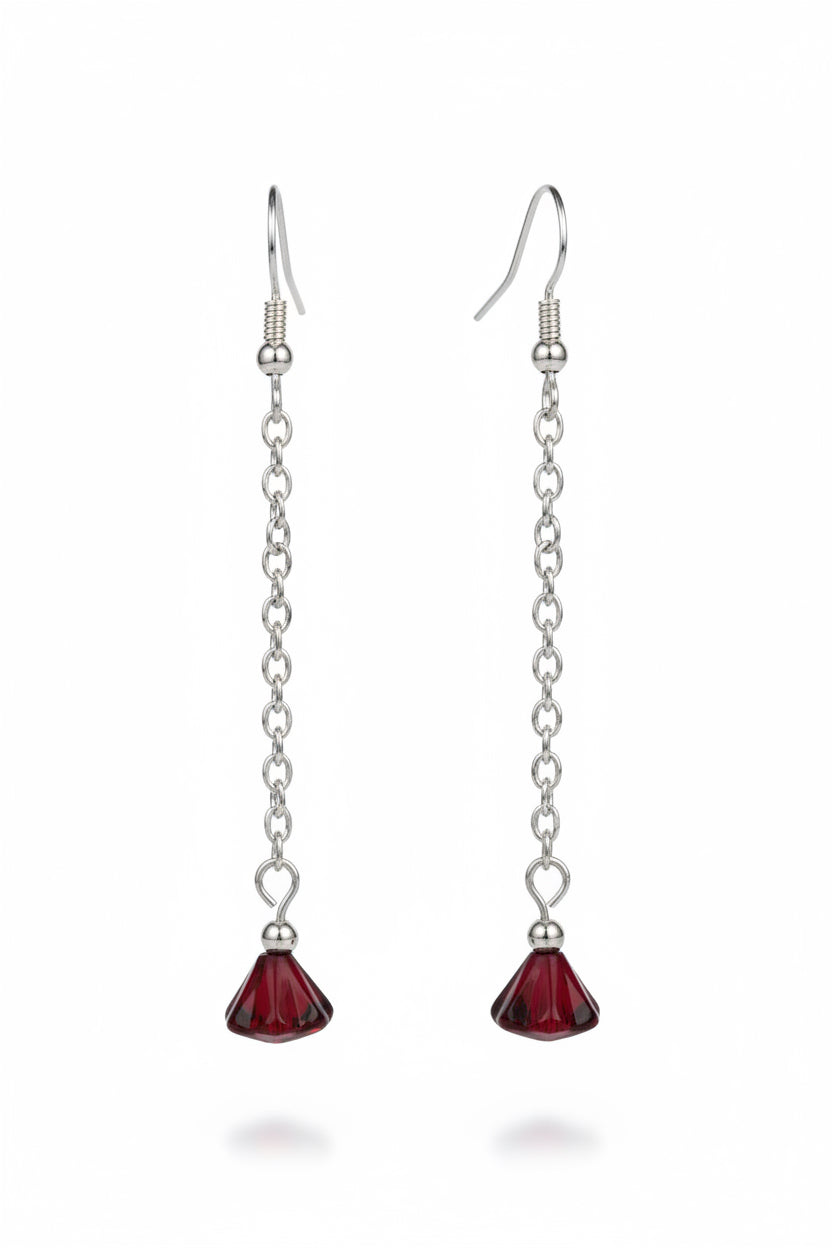 A pair of long drop earrings with silver-tone chain links and faceted dark red crystal pendants, shown against a black background.