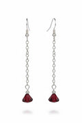 A pair of long drop earrings with silver-tone chain links and faceted dark red crystal pendants, shown against a black background.