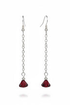 A pair of long drop earrings with silver-tone chain links and faceted dark red crystal pendants, shown against a black background.