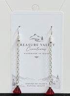 Treasure Valley Creations handmade dangle earrings with silver-toned chains and red faceted crystal pendants, displayed on a branded white backing card.