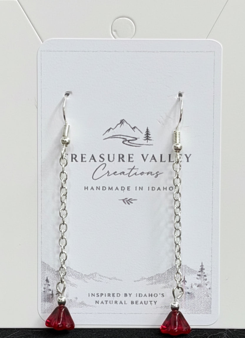 Treasure Valley Creations handmade dangle earrings with silver-toned chains and red faceted crystal pendants, displayed on a branded white backing card.