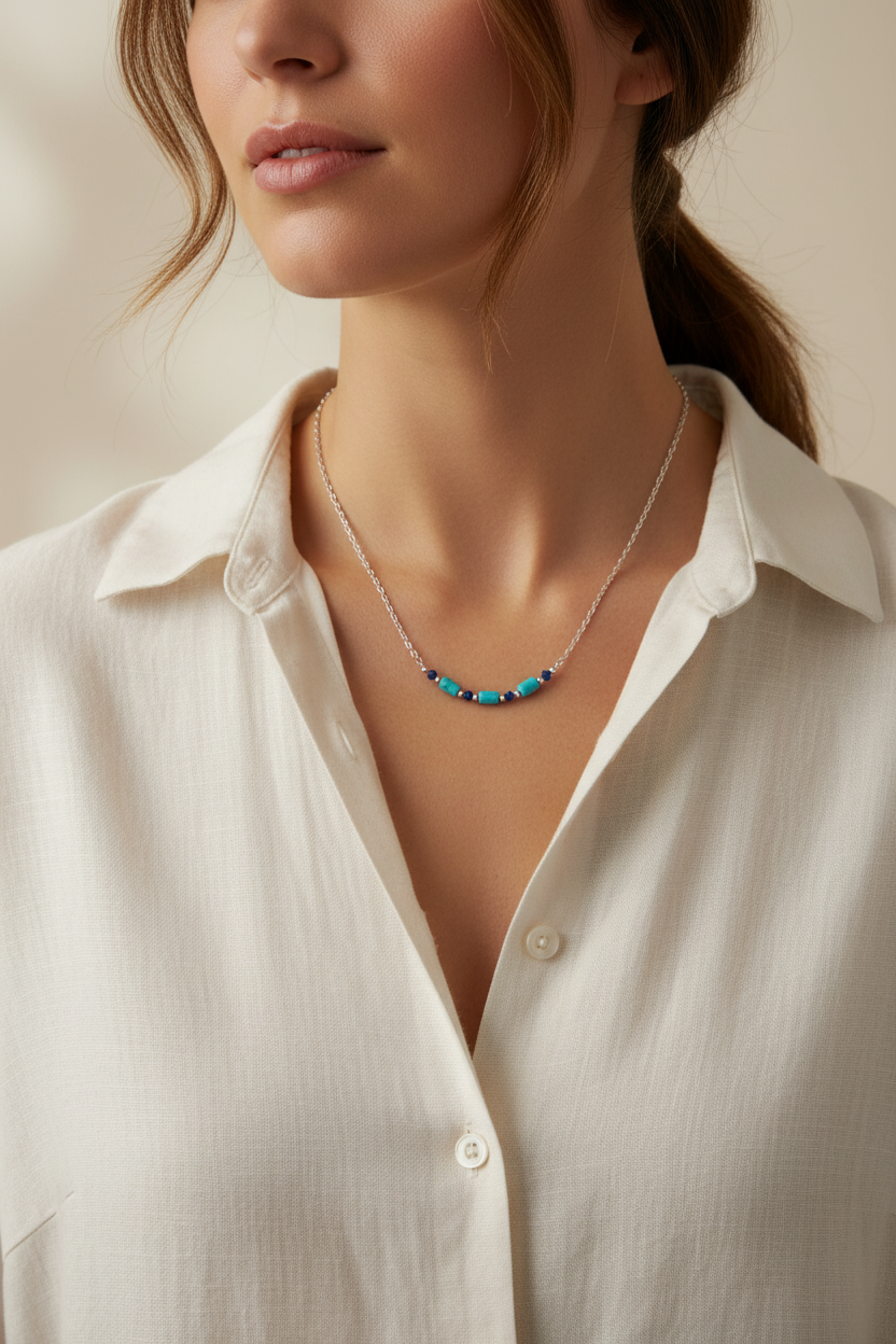 Necklace with blue  beads worn by a person in a white shirt against a neutral background