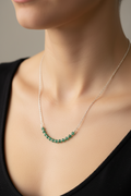 Necklace with green beads worn by a person against a neutral background