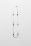 Necklace with green beads on a white fabric background