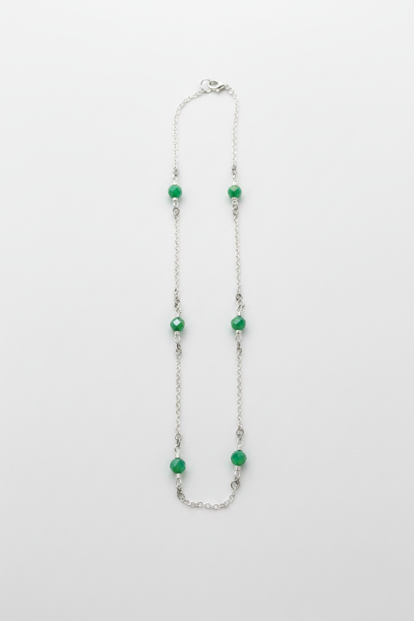 Necklace with green beads on a white fabric background