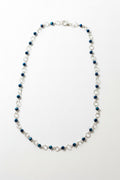 A beaded chain necklace with alternating dark blue faceted beads and silver-toned metal links, displayed on a plain light gray surface.