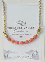 Treasure Valley Creations handmade necklace featuring pink round beads and gold spacer beads on a gold chain, displayed on its white backing card.
