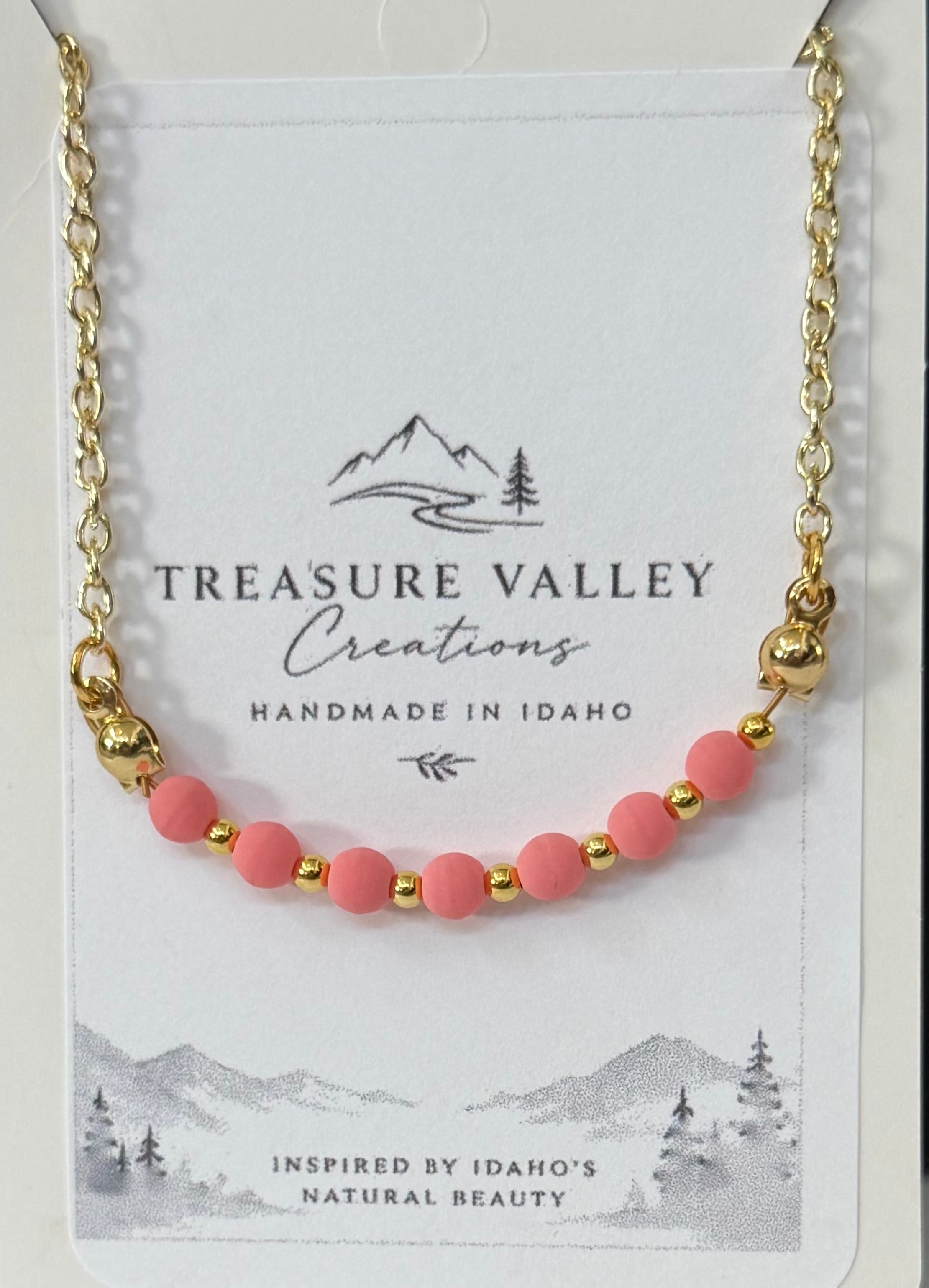 Treasure Valley Creations handmade necklace featuring pink round beads and gold spacer beads on a gold chain, displayed on its white backing card.