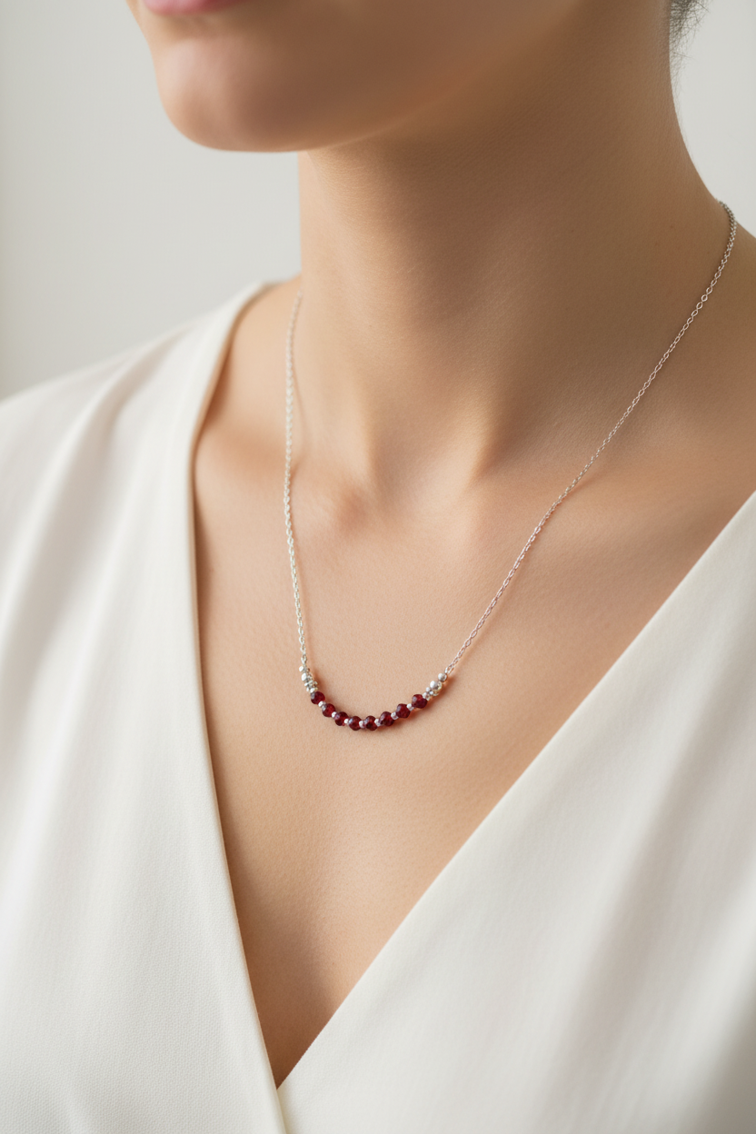 Necklace with red beads worn by a model in a white dress