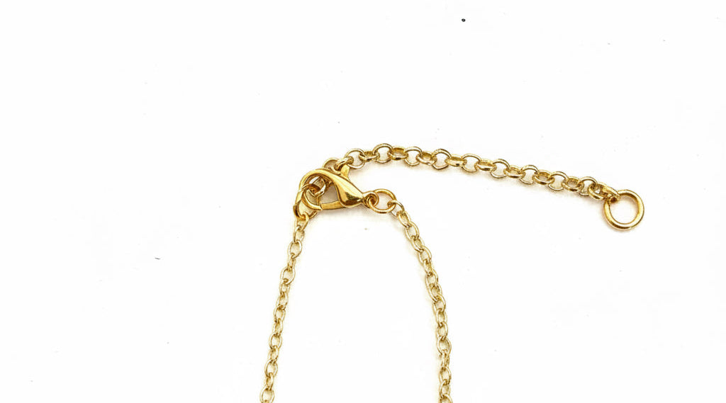 A close-up of a gold chain extender with a lobster clasp and a small ring, shown on a plain white background.