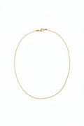 Gold necklace on a light beige fabric background