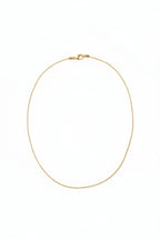 Gold necklace on a light beige fabric background