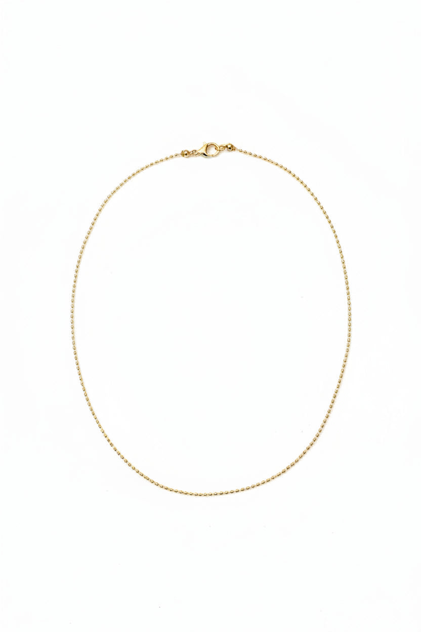 Gold necklace on a light beige fabric background