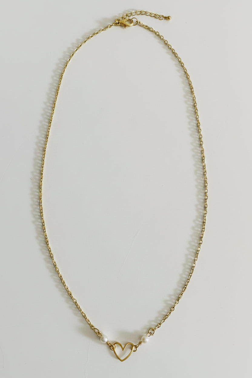 A delicate gold chain necklace with a small open heart charm and a tiny pearl accent, displayed on a plain light gray background.