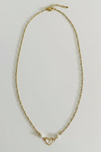 A delicate gold chain necklace with a small open heart charm and a tiny pearl accent, displayed on a plain light gray background.
