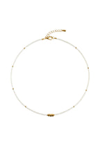 Pearl necklace with gold clasp on a white fabric background