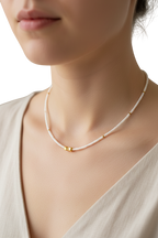 Pearl necklace with gold accents worn by a model against a neutral background