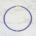 Blue beaded necklace with a gold clasp on a beige surface