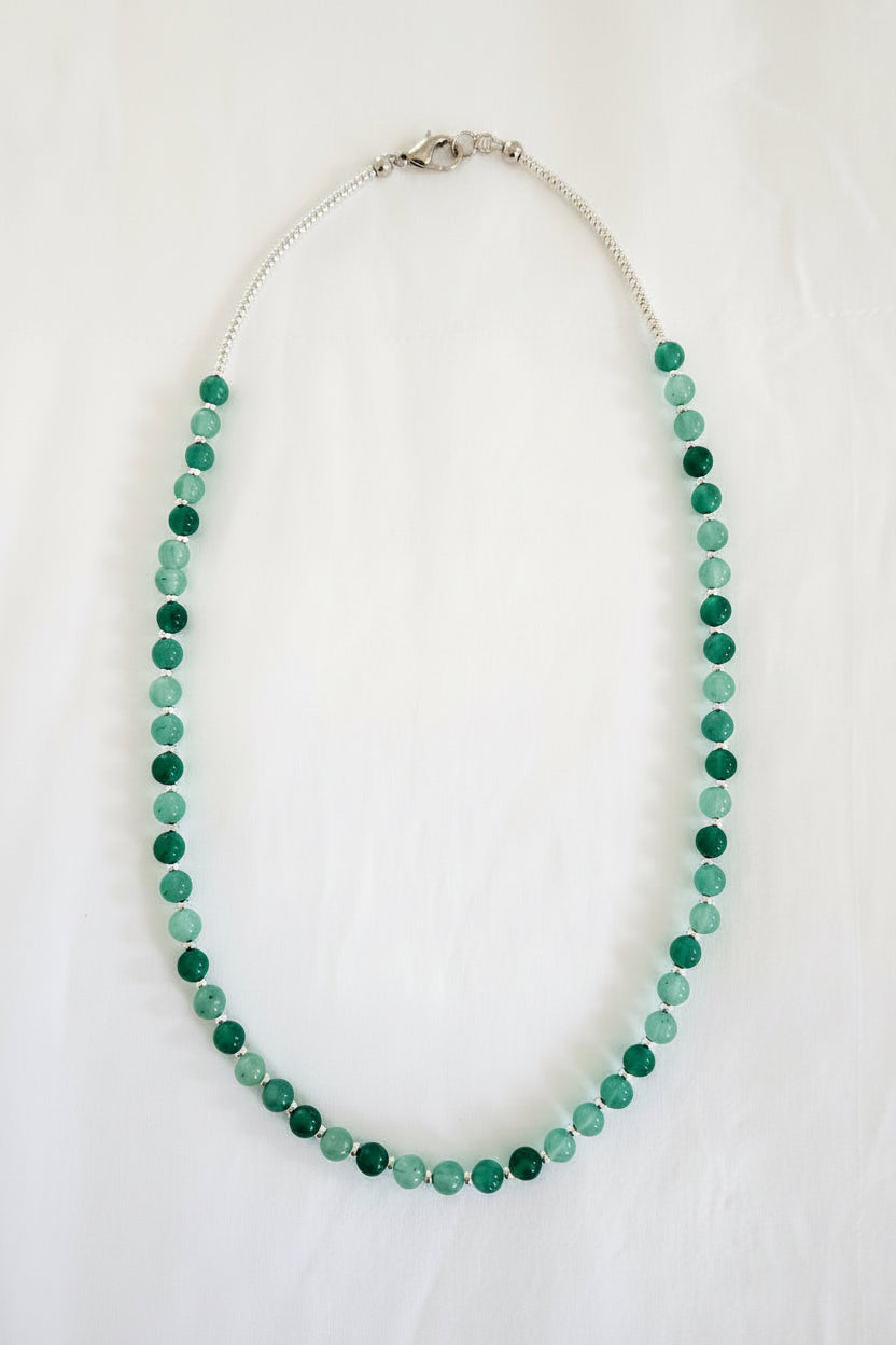 Green beaded necklace on a textured white surface