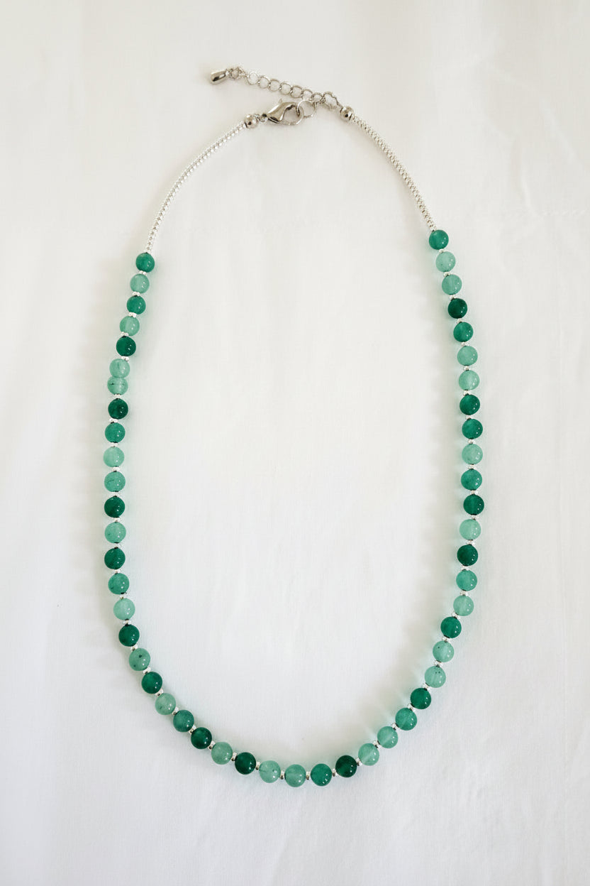Green beaded necklace on a textured white surface