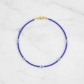 Blue beaded necklace with gold clasp on a white background