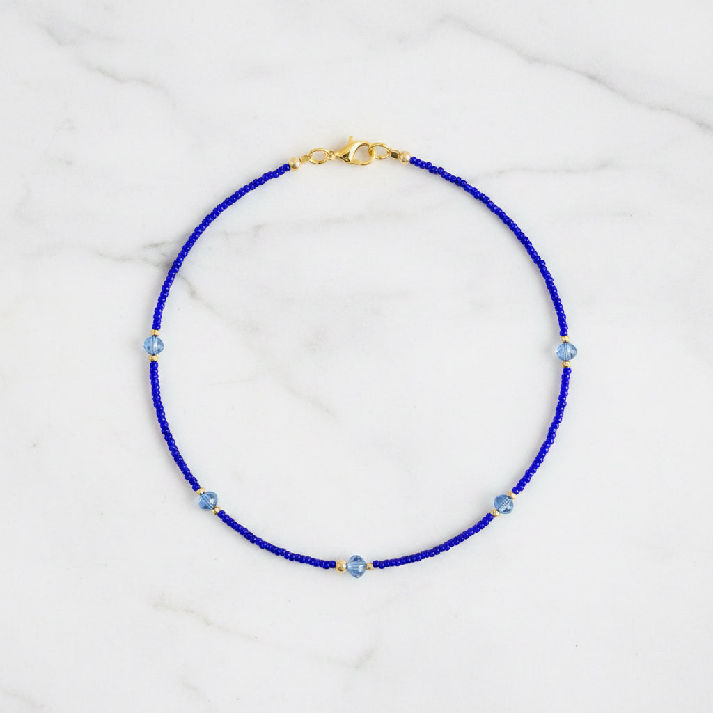 Blue beaded necklace with gold clasp on a white background
