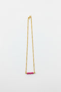 Gold necklace with pink beads on a white background