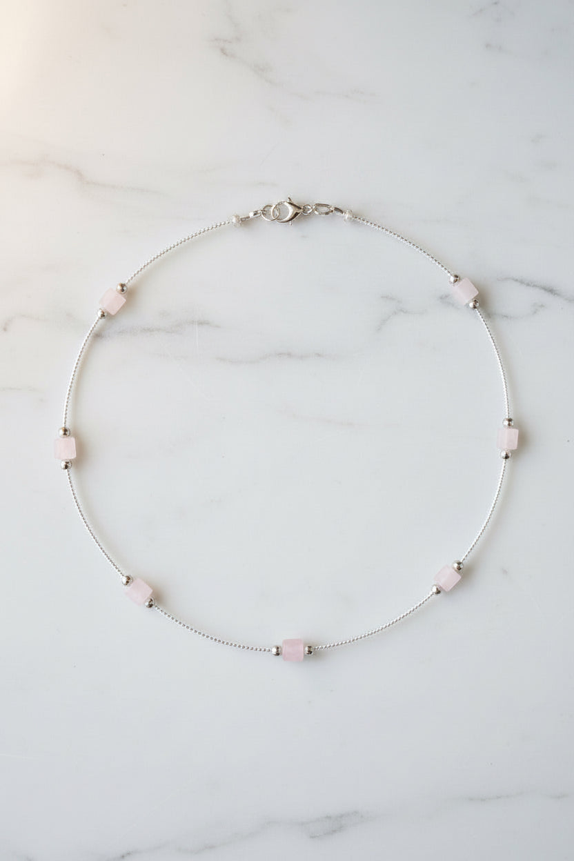 Silver necklace with beads on a beige fabric background