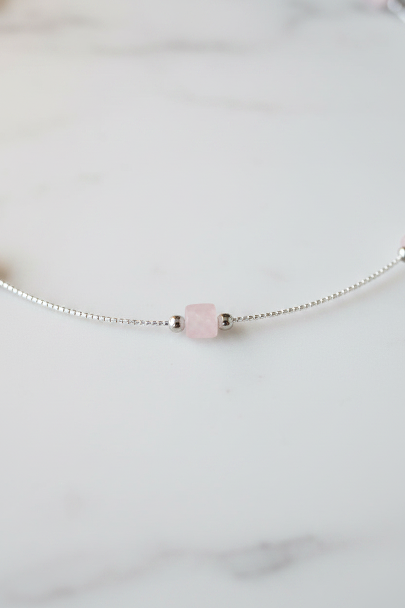 Necklace with a pink bead on a light gray background
