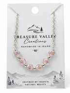 A silver-toned beaded necklace with pale pink and white beads, displayed on a white Treasure Valley Creations card against a light gray background.