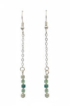 A pair of long silver-toned dangle earrings with chain links and small beads, including green faceted beads and pale mint beads, displayed on a black background.