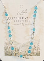 Handmade silver-tone necklace featuring faceted turquoise-blue crystal beads separated by polished silver links on an adjustable chain.