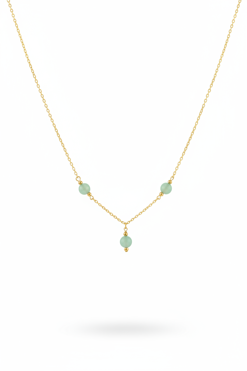A delicate gold chain necklace featuring three small, light green faceted beads spaced along the chain, with a smaller green bead hanging from the center, set against a plain white background.