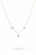 A delicate gold chain necklace featuring three small, light green faceted beads spaced along the chain, with a smaller green bead hanging from the center, set against a plain white background.