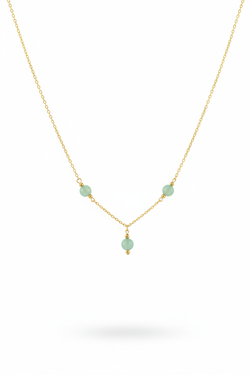 A delicate gold chain necklace featuring three small, light green faceted beads spaced along the chain, with a smaller green bead hanging from the center, set against a plain white background.
