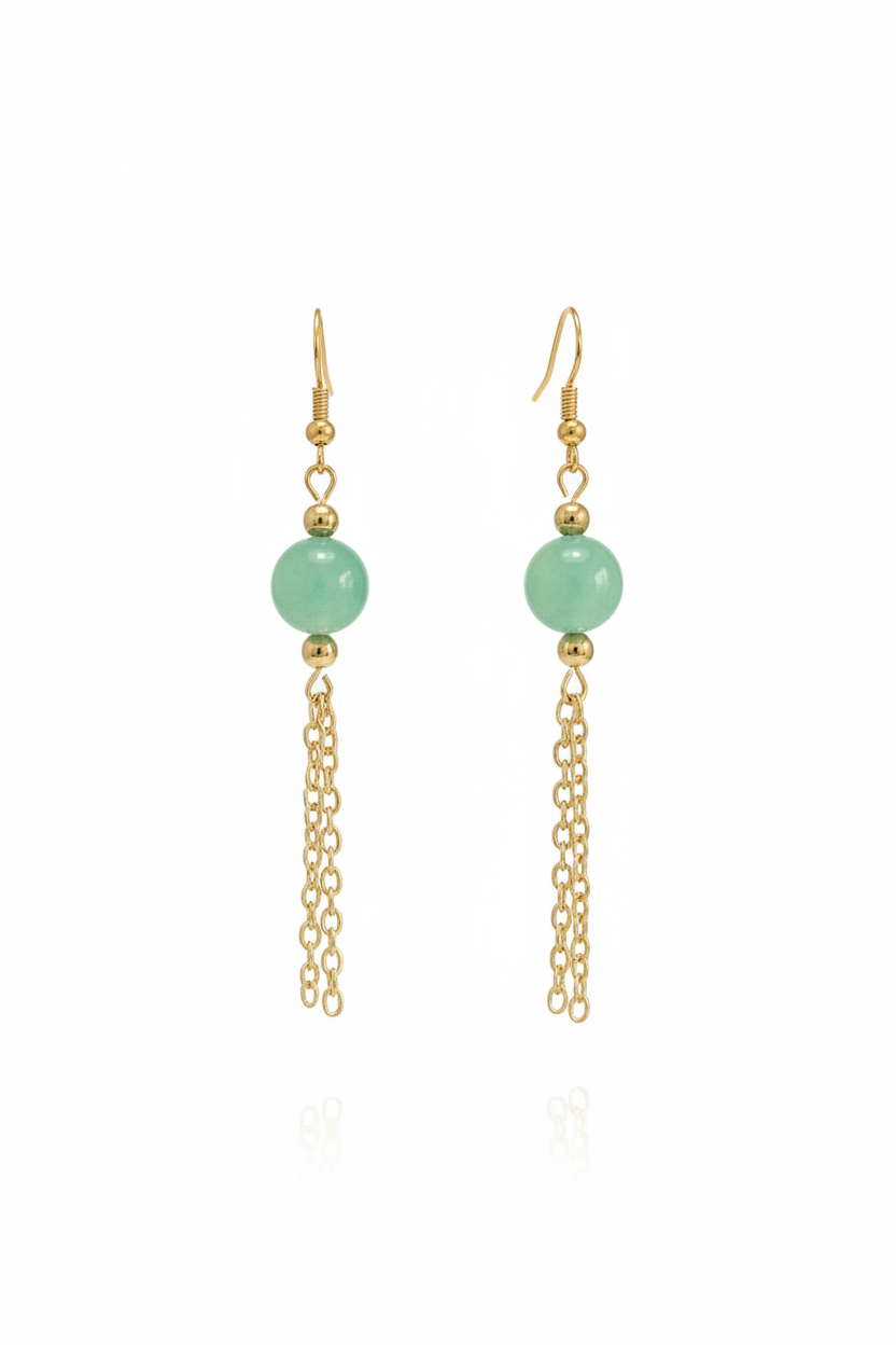 A pair of gold dangle earrings featuring a smooth, light green round bead and a delicate gold chain dangle, shown against a plain white background with a faint reflection below.
