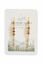 A pair of gold-tone beaded drop earrings with iridescent pink, yellow, and green beads, displayed on a white card from Treasure Valley Creations.