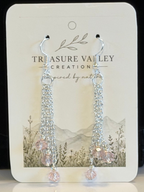 A pair of silver-tone dangle earrings with clear faceted beads and light pink crystal drops, displayed on a white Treasure Valley Creation branded card.