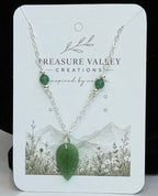 A small jewelry display card showing a green pendant necklace.